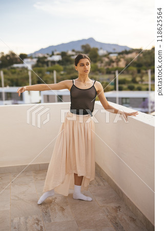 A Graceful Ballerina is elegantly Posing on a Beautiful Outdoor Terrace in the Sunshine 118625564