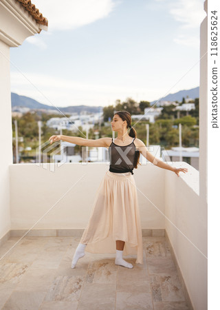 An Elegant Ballerina Gracefully Posing on a Beautiful Scenic Balcony Overlooking Nature 118625624