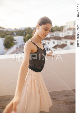 A Graceful Young Dancer Posing Elegantly on a Beautiful Balcony at Glorious Sunset Time A Graceful Young Dancer Posing Elegantly on a Beautiful Balcony at Glorious Sunset Time 118625637