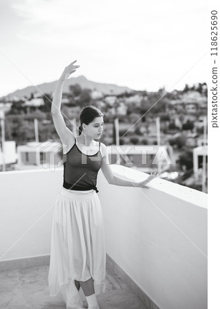 An Elegant Ballet Dancer is Gracefully Posing Outdoors Against a Monochrome Backdrop 118625690