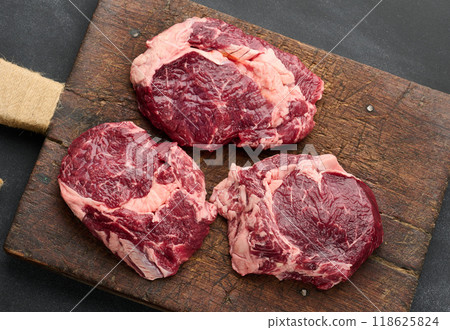 Raw beef tenderloin lies on a cutting board on a black table 118625824