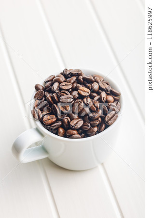 Roasted coffee beans in coffee cup on white table. 118625997