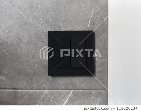 A modern black switch on a white wall background with gray granite. Technologies and electrics in the interior of the room 118626134