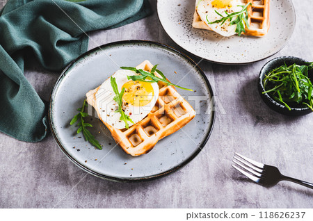 Homemade crispy waffles with egg and arugula on a plate on the table 118626237