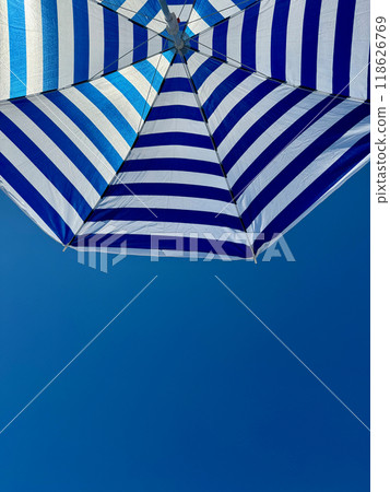 Fragment of white and blue striped beach umbrella close up against clear blue sky with text space Fragment of white and blue striped beach umbrella close up against clear blue sky with text space 118626769