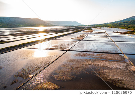 Sunrise over salt pans reflecting golden light in serene landscape 118626970