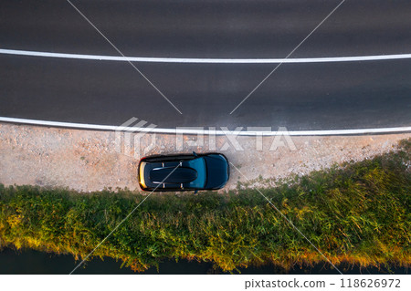 Aerial view of a car parked beside a winding road with a roof rack and grassy area. Aerial view of a car parked beside a winding road with a roof rack and grassy area. 118626972