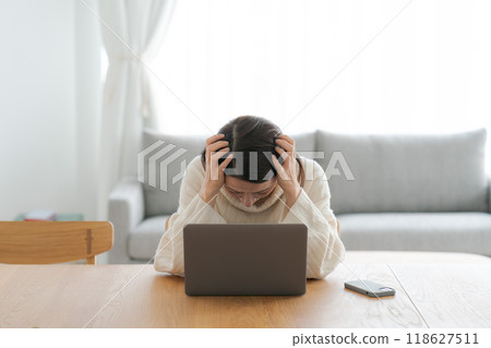 A woman who is depressed looking at a computer 118627511