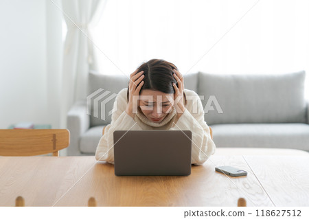 A woman who is depressed looking at a computer 118627512
