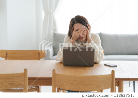 A woman who is depressed looking at a computer 118627513