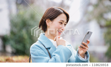Woman using a smartphone (winter clothes, jacket, coat) Woman using a smartphone (winter clothes, jacket, coat) 118628918