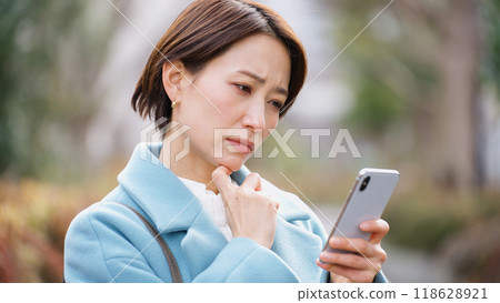 Woman using a smartphone (winter clothes, jacket, coat) 118628921