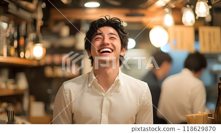 A young man in a shirt laughing out loud at an izakaya 118629870