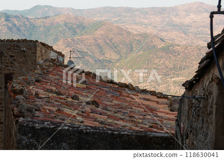 Rustic village rooftops with mountain backdrop in Mediterranean setting 118630041