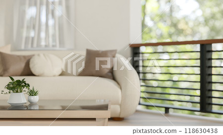 A close-up of a coffee table in a comfortable living room, featuring a modern sofa and a balcony. 118630438