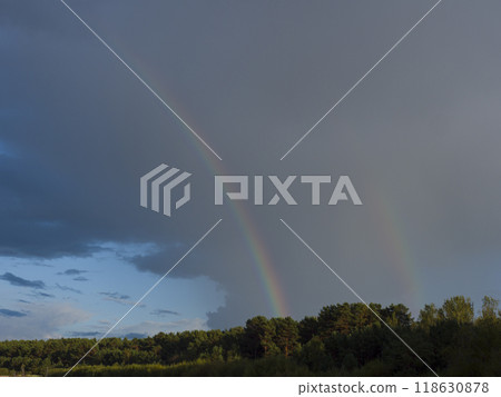 Amid dark clouds, a brilliant rainbow emerges its colors vivid against the stormy backdrop. As the rainbow stretches across the sky, the contrast with the clouds enhances the scene's dramatic beauty. Amid dark clouds, a brilliant rainbow emerges its colors vivid against the stormy backdrop. As the rainbow stretches across the sky, the contrast with the clouds enhances the scene's dramatic beauty. 118630878