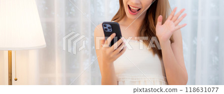 Young asian woman walking using smart phone for video call in living room at home. 118631077