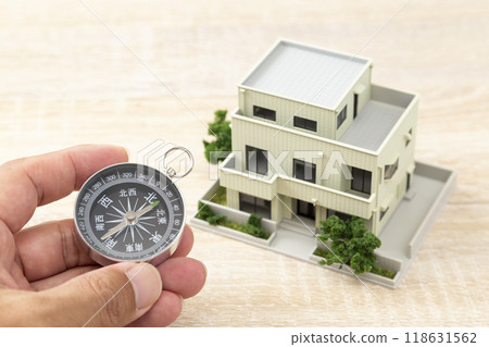 拿著指南針和房屋模型的手 118631562