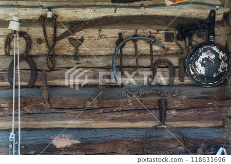 Old Slavic tools and tools hang on the wall of a log house Old Slavic tools and tools hang on the wall of a log house 118631696