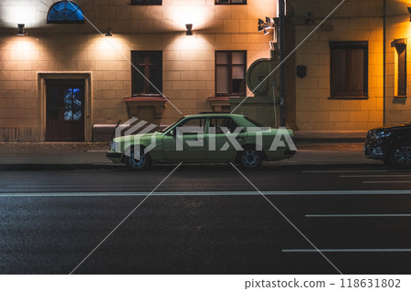 An old car is parked on the side of the road, at night in the city An old car is parked on the side of the road, at night in the city 118631802