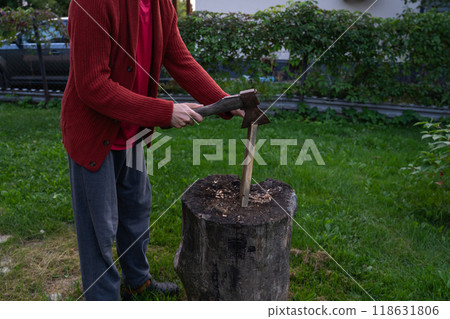 A man is chopping wood for a bonfir A man is chopping small firewood. Evening 118631806