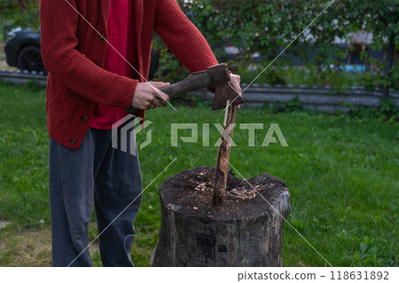 A man is chopping wood for a bonfir A man is chopping small firewood. Evening A man is chopping wood for a bonfir A man is chopping small firewood. Evening 118631892
