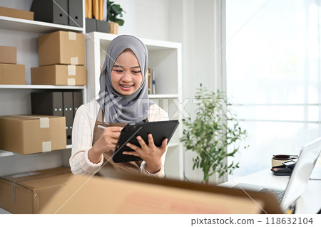 Cheerful young muslim woman small business owner taking orders from customer on digital tablet Cheerful young muslim woman small business owner taking orders from customer on digital tablet 118632104