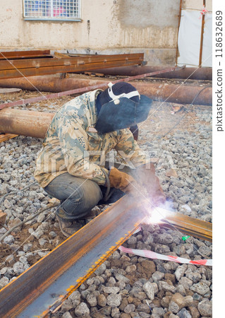 Welder in mask welding metal construction on open air. Welder in mask welding metal construction on open air. 118632689