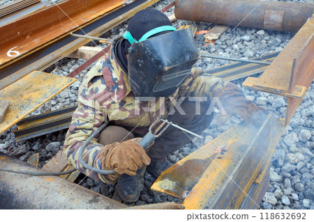 Welder in mask welding metal construction on open air. Welder in mask welding metal construction on open air. 118632692