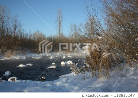 Winter river in snow landscape. Frozen river water in winter 118633147