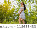 Pregnant woman holding showing belly baby bump smiling happy in 3rd trimester in spring forest nature. Asian expectant mom holding tummy in happiness. Healthy pregnancy concept 118633433