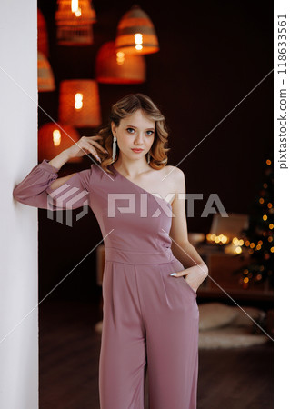 Beautiful woman in pink jumpsuit posing in Christmas interior. 118633561