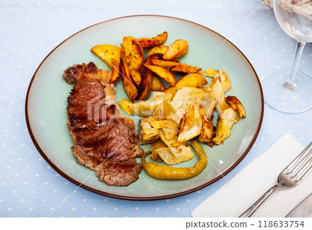 Beef steak with potatoes and artichokes on wooden board 118633754