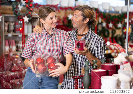 Happy married couple chooses New Year and Christmas decorations for tree and their home 118633862