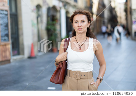 Woman in casual clothes walking through summer city street Woman in casual clothes walking through summer city street 118634020