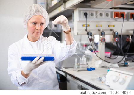 Female pharmacist researcher waiting for color change in test tube while conducting experiment in laboratory 118634034