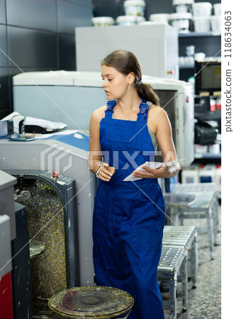 Saleswoman servicing paint mixing machine in construction supermarket 118634063