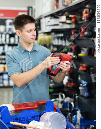 Male customer choosing electric drill in hardware store 118634201