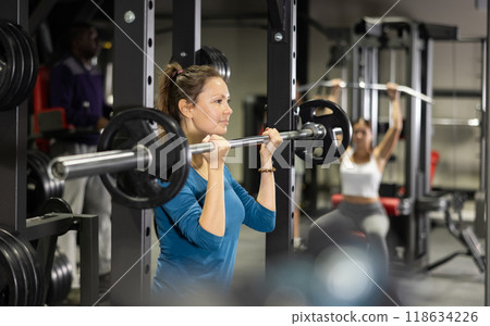 Sportswoman doing exercises with a barbell in gym 118634226