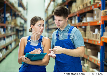 Girl check papers invoices with guy and revise availability of goods in paint and varnish stock Girl check papers invoices with guy and revise availability of goods in paint and varnish stock 118634269