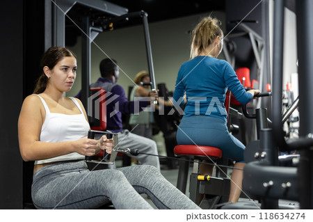 Caucasian woman doing exercises on cable row machine in gym Caucasian woman doing exercises on cable row machine in gym 118634274