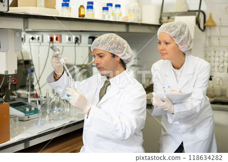 Man and woman scientists chemists conduct experiments in the laboratory Man and woman scientists chemists conduct experiments in the laboratory 118634282