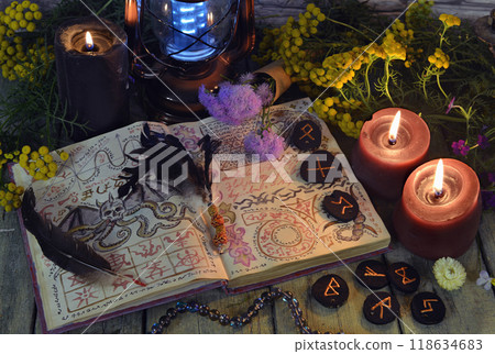 Mystic still life with book of spell, runes and witchy ritual objects on old altar table. Occult, esoteric, wicca, Halloween and gothic concept. No foreign language, all symbols are fictional Mystic still life with book of spell, runes and witchy ritual objects on old altar table. Occult, esoteric, wicca, Halloween and gothic concept. No foreign language, all symbols are fictional 118634683
