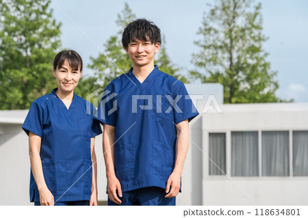 Male and female medical staff (occupational therapists and nurses) wearing scrubs in front of a hospital or facility 118634801