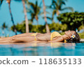 Sunbathing woman relaxing under sun in luxury on travel beach vacation at infinity pool at luxury hotel resort 118635133