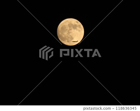 A jetliner flying over the harvest moon 118636345