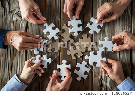A group of people holding jigsaw puzzle pieces together on a wooden table 118636527