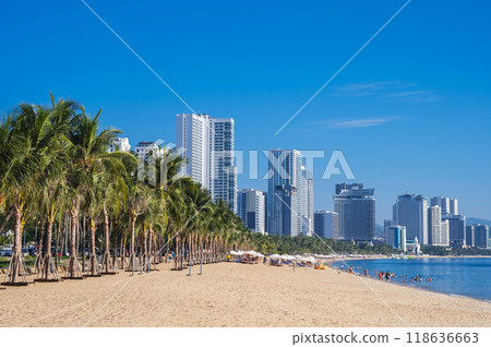 Sandy beach with palm trees by the sea in resort town with skyscrapers in summer in Nha Trang in Vietnam Sandy beach with palm trees by the sea in resort town with skyscrapers in summer in Nha Trang in Vietnam 118636663