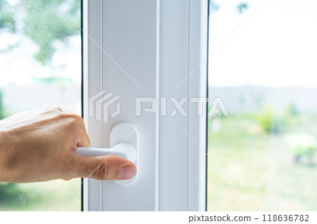 The hand holds the handle of a plastic double-glazed window, closing and opening the window with a rotary mechanism, the position of the handle for ventilation, micro-ventilation The hand holds the handle of a plastic double-glazed window, closing and opening the window with a rotary mechanism, the position of the handle for ventilation, micro-ventilation 118636782