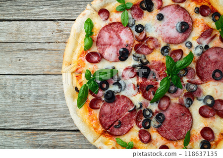 Pizza with mozzarella cheese , salami sausages , olives , and basil Pizza with mozzarella cheese , salami sausages , olives , and basil 118637135